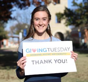 A woman holding a "thank you" sign for Giving Tuesday at Howard Payne University. | HPU