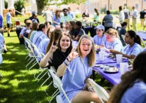 Group of people from Howard Payne University enjoying an outdoor event with food at long tables. | HPU