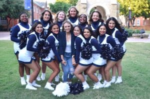 A group of Howard Payne University cheerleaders posing together with a woman in the center who is not in uniform. | HPU