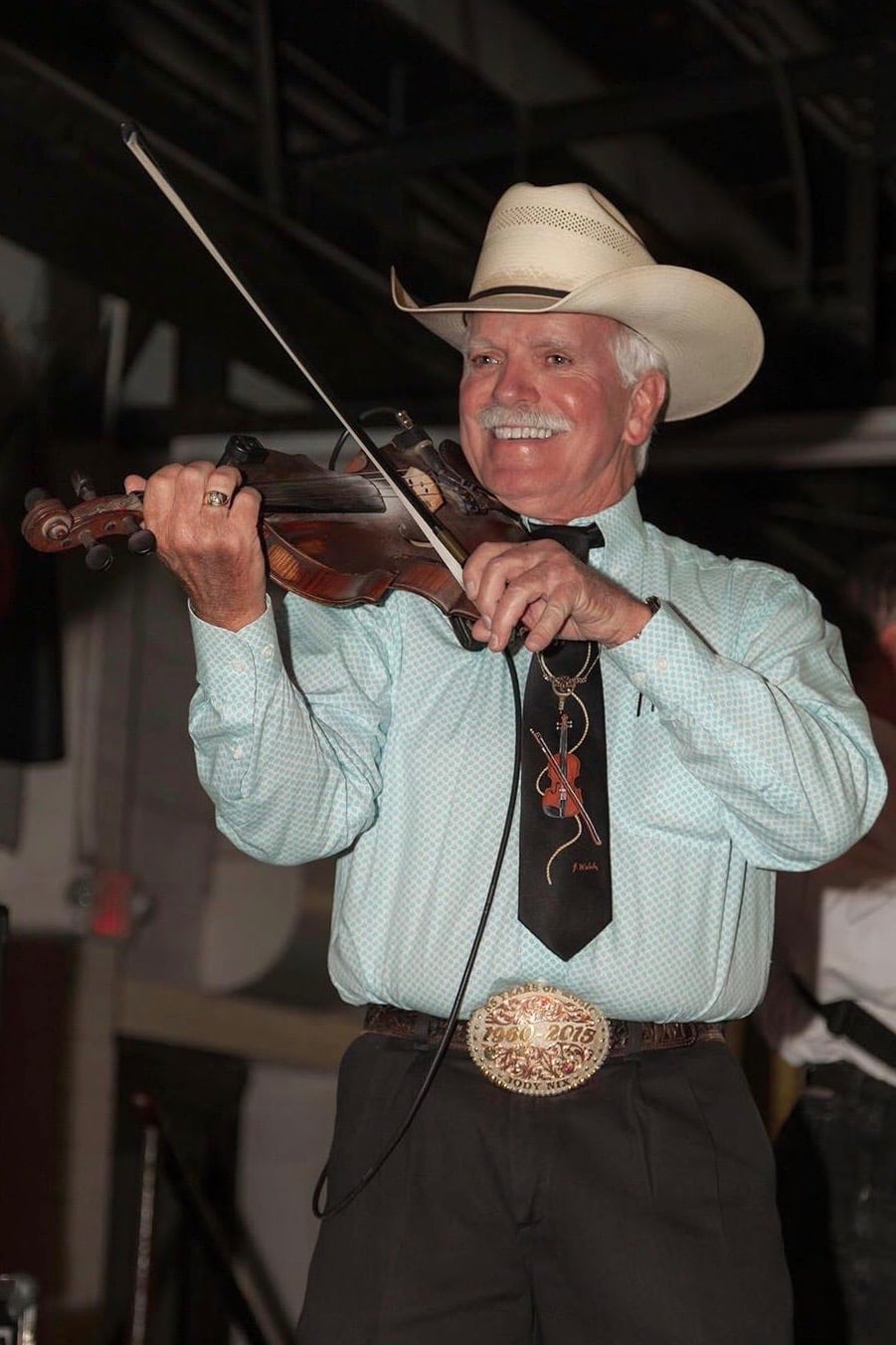 A smiling man wearing a cowboy hat and representing Howard Payne University plays the violin. | HPU