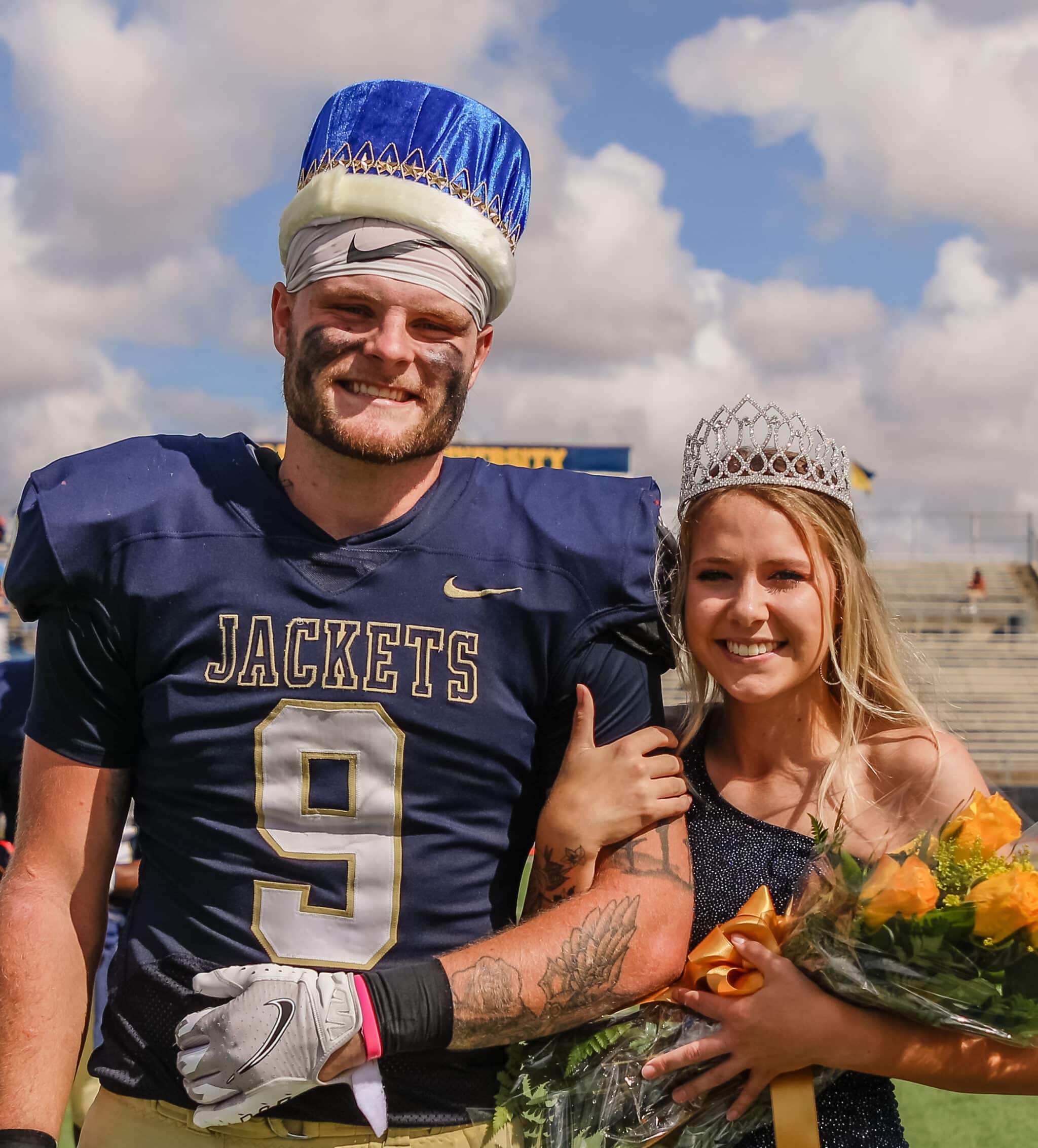 Football player from Howard Payne University wearing number 9 jersey and homecoming queen with tiaras on a sunny day. | HPU