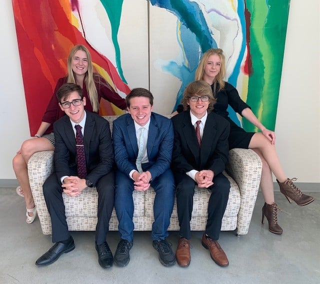 Five individuals posing in formal attire in front of a colorful abstract painting at Howard Payne University. | HPU