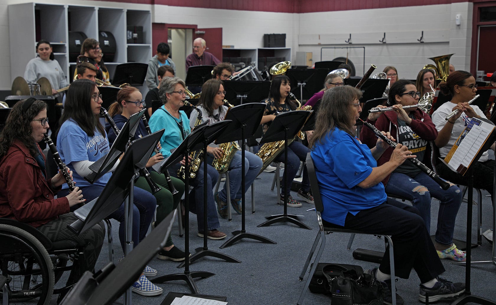 A diverse group of individuals from Howard Payne University practice together in a band rehearsal room, playing a variety of wind and brass instruments. | HPU