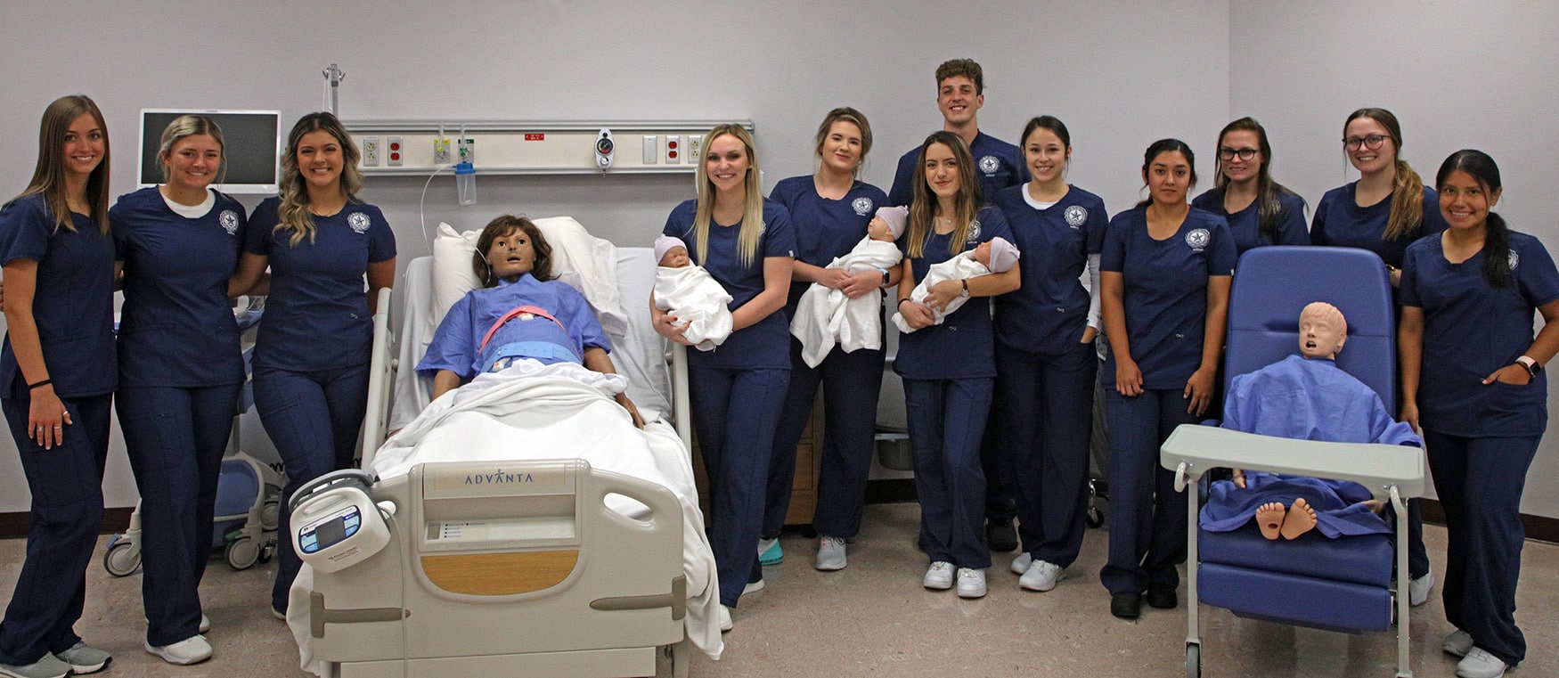 Group of nursing students from Howard Payne University posing with medical training mannequins in a simulation lab. | HPU