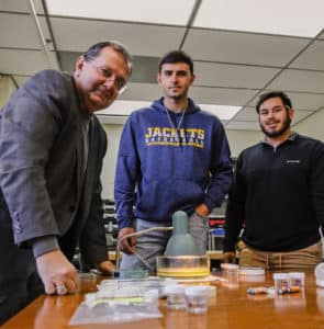 Professor and students at Howard Payne University examining equipment in a laboratory setting. | HPU