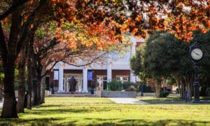 Autumn colors frame a peaceful Howard Payne University campus scene, complete with a clock tower and walking students. | HPU