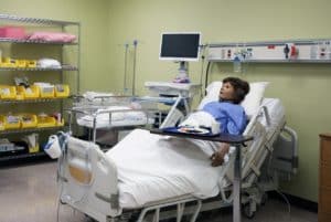 A patient resting in a hospital bed with a Howard Payne University meal tray nearby. | HPU