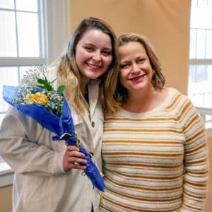 Two smiling women posing together at Howard Payne University, one holding a bouquet of flowers. | HPU