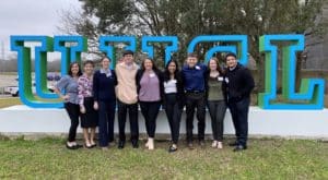 Group of people posing together in front of large letters that spell "Howard Payne University. | HPU