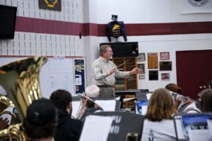 A conductor leading a band rehearsal in Howard Payne University's school gymnasium. | HPU