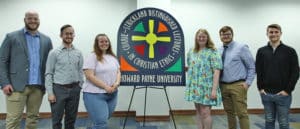Group of six individuals posing for a photo in front of a banner for the Currie-Strickland Distinguished Lectures in Christian Ethics at Howard Payne University. | HPU