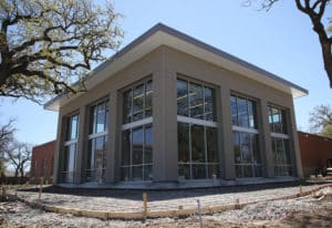 Modern building under construction at Howard Payne University with large glass windows and unfinished landscaping. | HPU