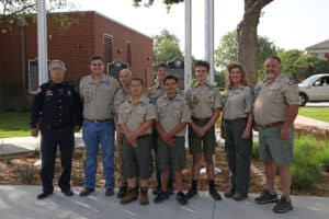 Group of boy scouts with leaders and a police officer standing in front of Howard Payne University. | HPU