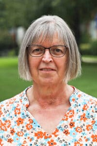 Senior woman with glasses and gray hair, a Howard Payne University alumna, standing outdoors. | HPU