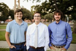 Three young men from Howard Payne University smiling outdoors, dressed in semi-formal attire. | HPU