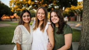 Three smiling women standing together outdoors at Howard Payne University. | HPU