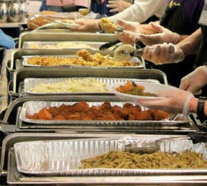 Volunteers from Howard Payne University serving a variety of foods at a community meal event. | HPU