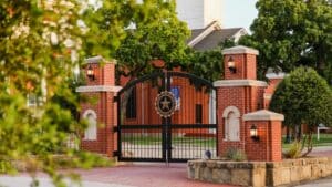 Ornate metal gate with Howard Payne University emblem, flanked by brick pillars, at the entrance to a property. | HPU