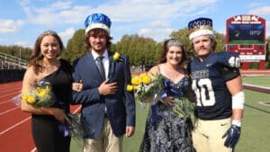 Homecoming royalty posing on a sports field at Howard Payne University with a stadium in the background. | HPU