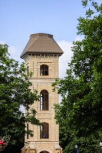 Old Main Tower appears on HPU's campus behind green trees.